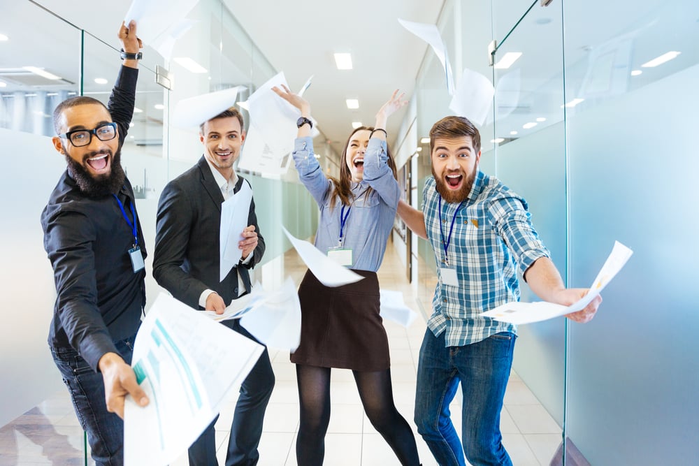 Group of joyful excited business people throwing papers and having fun in office Group of joyful excited business people throwing papers and having fun in office